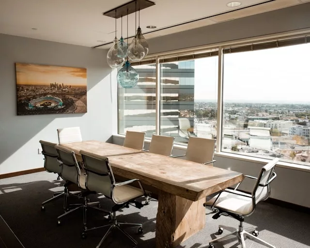 meeting room with beige wooden conference table and office chairs around it